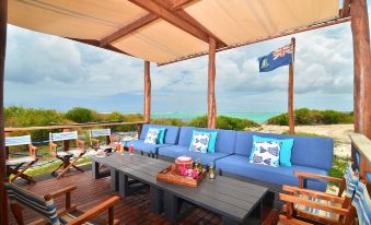 a wooden deck with a large blue couch and chairs , surrounded by various outdoor furniture at Anegada Beach Club