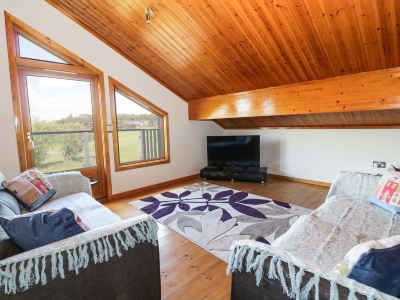 a cozy living room with a wooden ceiling , a couch , and a tv . also a dining table in the room at Moon Face