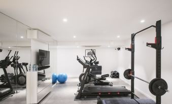 a well - equipped home gym with various exercise equipment , including a treadmill , weights , and a television at Au Clos du Lac