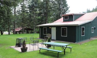 a green house with a red roof has a picnic table and chairs in the front yard at Lone Fir Resort