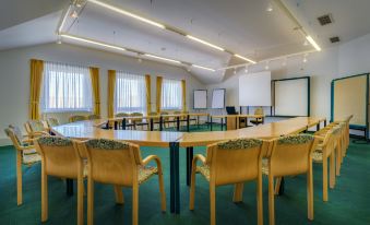 a conference room with several chairs arranged in a semicircle around a long table , and a projector screen on the wall at Hotel Astor