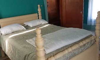 a bed with a wooden headboard and footboard is shown in a bedroom with green walls at The Old Victorian Inn