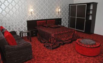 a luxurious bedroom with red carpet , black bed , and white walls decorated with wallpaper , accompanied by a couch and coffee table at Sword Hotel