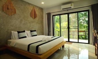 a large bedroom with a king - sized bed and a sliding glass door leading to a balcony at Baiboon Resort