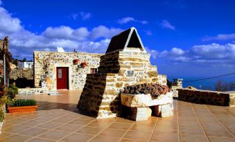 a stone building with a red door and a blue sky in the background , near the ocean at Villa Rosa
