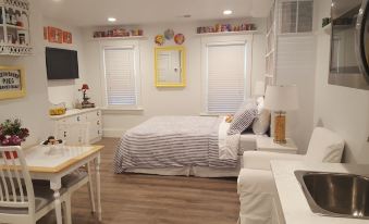 a clean , white bedroom with a bed , nightstands , and a tv , as well as a desk and chair at Devils Lake Inn