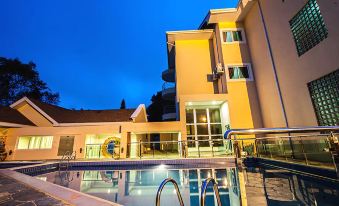 a large swimming pool is surrounded by a yellow building with blue lights illuminating it at Golden Bean Hotel