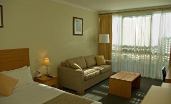 a hotel room with a couch , bed , and table in the foreground , while a window with curtains in the background at Admiralty Inn