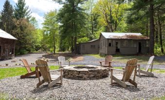 a stone fire pit surrounded by wooden chairs on a gravel area , with trees in the background at Stonehill's Farmhouse