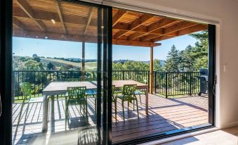 a wooden deck with green chairs and a glass door leading to a pool area at Vineyard Views