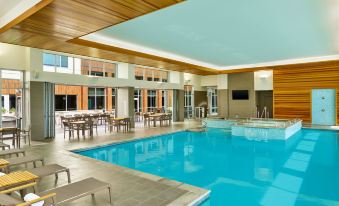 an indoor swimming pool with a large window , surrounded by tables and chairs , in a modern building at Element Fargo