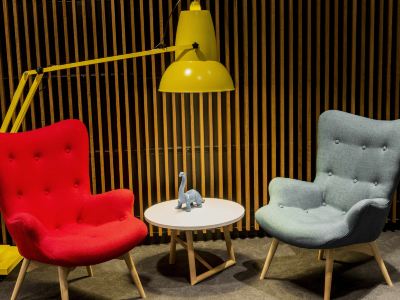 a room with two red chairs , one on the left side and one on the right side , and a yellow lamp hanging above the table at Ibis Melbourne Hotel and Apartments