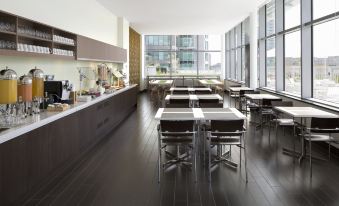 a modern dining area with tables and chairs , as well as a kitchen counter and cabinets at Element Vancouver Metrotown