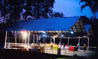 a group of people gathered around a dining table in a tent , enjoying a meal together at Baanrai Riverkkwai Resort