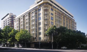 a large , modern building with multiple floors and large windows , situated on a busy city street at Vibe Hotel Sydney
