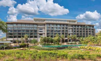 a large , modern hotel building with a swimming pool and lush greenery in the background at Gran Melia Arusha