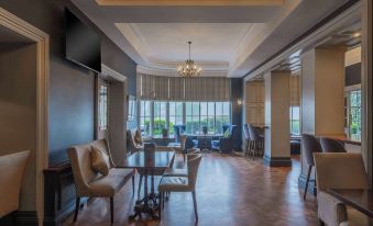a modern living room with large windows , wooden floors , and comfortable seating arrangements , as well as a dining area with tables and chairs at Bunratty Castle Hotel