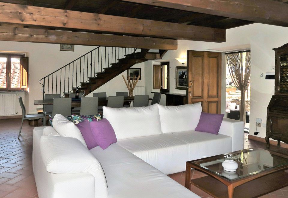 a modern living room with a white sectional sofa , wooden beams , and a staircase leading to the second floor at Villa