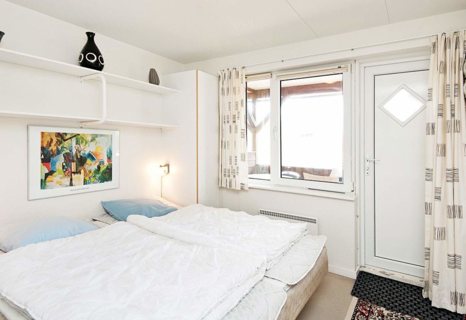 a white bedroom with two beds , one on the left and one on the right side of the room at Henne
