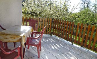 a patio with a wooden fence , a table with chairs , and a tree in the background at Zerna
