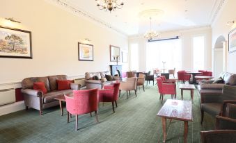 a large , well - lit room with multiple couches and chairs arranged in various positions , creating a cozy and inviting atmosphere at Columba Hotel Inverness by Compass Hospitality