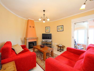 a cozy living room with two red couches , a fireplace , and a flat - screen tv mounted on the wall at Joli Joli Photo