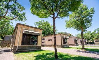 a row of modern , beige - colored buildings with wooden exterior and large windows , surrounded by trees and grass at Adelaide Caravan Park - Aspen Holiday Parks