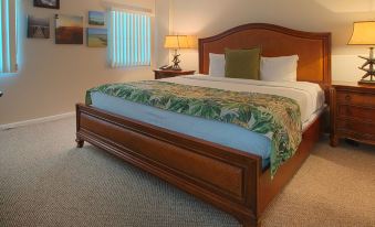 a large wooden bed with a green and white blanket in a bedroom with carpeting at Mangroves