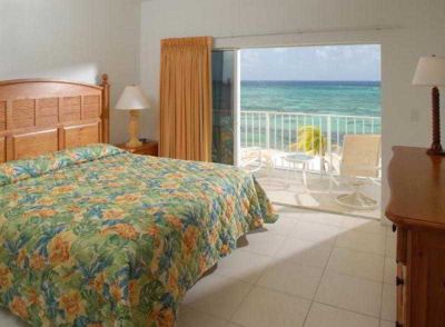 a bedroom with a bed , lamp , and sliding glass door leading to an ocean view balcony at Wyndham Reef Resort Grand Cayman