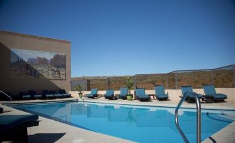 a large outdoor swimming pool surrounded by lounge chairs , with a view of the desert in the background at Ticaboo Lodge