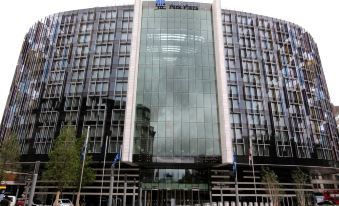 a large building with a modern design and glass windows , standing in front of a tree - lined street at Park Plaza Westminster Bridge London