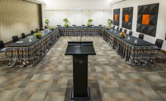 a large conference room with a long table , chairs , and a podium in the center at The Pearl South Pacific Resort