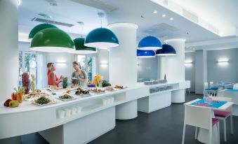 a modern food court with multiple tables and counters , each equipped with different colored hanging lights at Love Boat Hotel - the Original