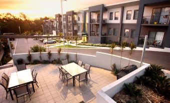 a modern apartment building with an outdoor patio area featuring a dining table and chairs at Quest Ipswich