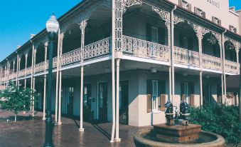 a large white building with multiple balconies and a fountain in front of it , surrounded by trees at St. James Hotel Selma, Tapestry Collection by Hilton