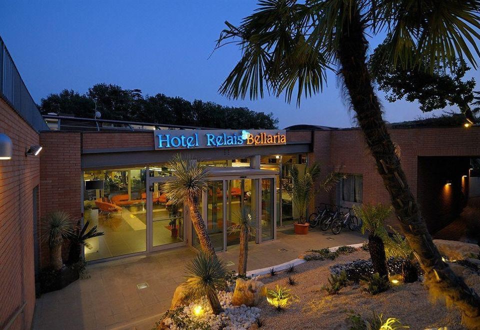 "a modern hotel building with palm trees and a sign reading "" hotel reale porto bianco "" at dusk" at Relais Bellaria Hotel & Congressi