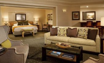 a hotel room with a bed , couch , dining table , and other furniture , including a table with a tray on it at Hyatt Regency Huntington Beach Resort and Spa