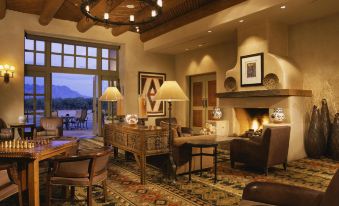 a spacious living room with a fireplace , wooden furniture , and a large window overlooking the mountains at Hyatt Regency Tamaya Resort and Spa