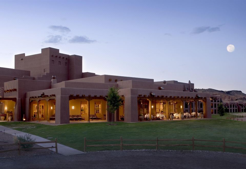 a large building with a pink facade and a thatched roof is illuminated by lights at dusk at Hyatt Regency Tamaya Resort and Spa