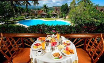 a table with food and drinks is set up in a room overlooking a pool at Badian Island Wellness Resort