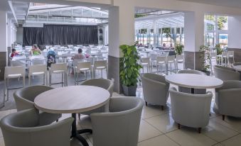 a restaurant with several tables and chairs , some of which are occupied by people sitting at them at Hotel Sorra Daurada Splash