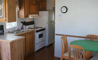 a small , well - equipped kitchen with a dining table and chairs , as well as a refrigerator and stove at Wilderness Presidential Resort