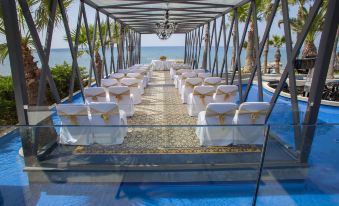 a long dining table set up for a wedding reception , with chairs arranged around it at The GrandResort - Limited Edition by Leonardo Hotels