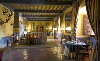 a luxurious dining room with a fireplace , marble table , and blue tablecloth , surrounded by elegant furniture at Parador de Jarandilla