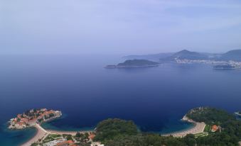 a panoramic view of a beautiful blue ocean with islands and buildings , captured from a high vantage point at Aman Sveti Stefan