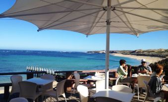 a man and a woman are sitting on a deck overlooking the ocean , enjoying each other 's company at Margarets Beach Resort