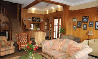 a cozy living room with wooden walls , a large couch , and a potted plant on the coffee table at Hundith Hill Hotel