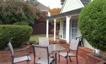 a patio with a table and chairs set up for outdoor dining , surrounded by trees at Asure Green Gables Motel