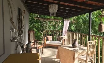 a covered patio with a wooden table , chairs , and a chandelier , surrounded by lush greenery at Hacienda Tres Casitas