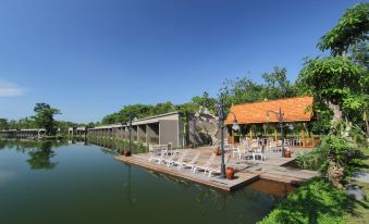 a large body of water surrounded by a wooden deck , with several lounge chairs placed along the shore at The Westlake Hotel & Resort Yogyakarta